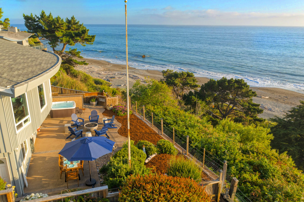 Amazing outdoor living with dining table, firepit with seating, hot tub - all overlooking the Pacific Ocean