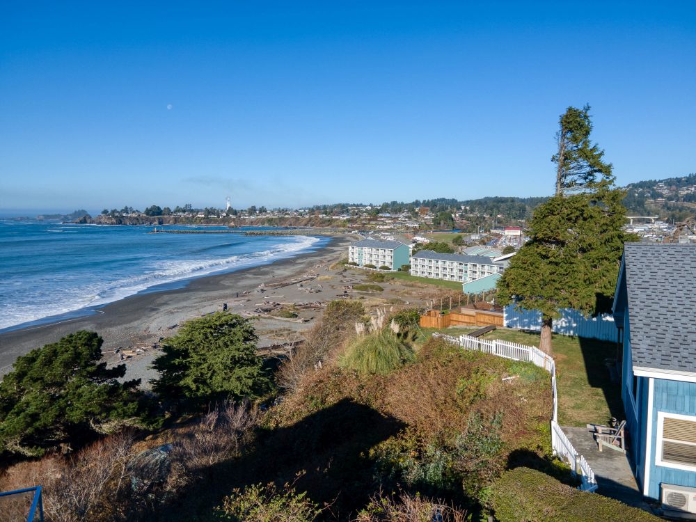 Aerial view showing the back of Sunset Cabin looking up the coast - with a hotel and Port of Brookings in the background
