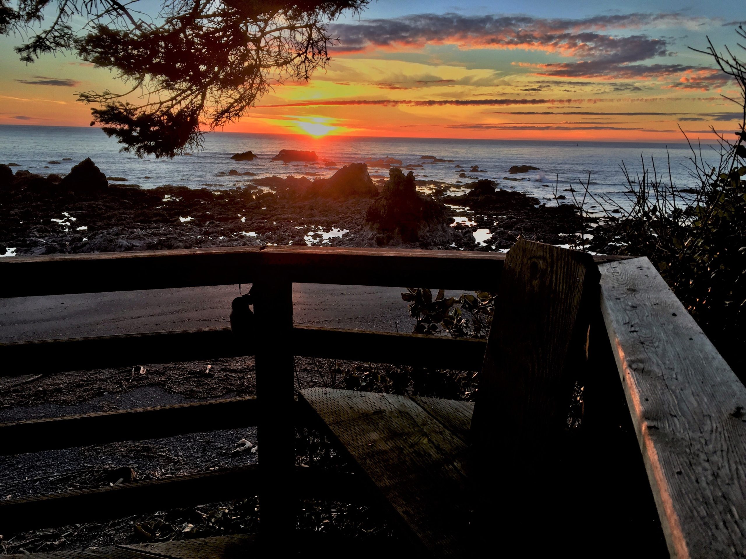 Sunset view of the ocean with deck railing in foreground at Pacific Edge in Brookings OR