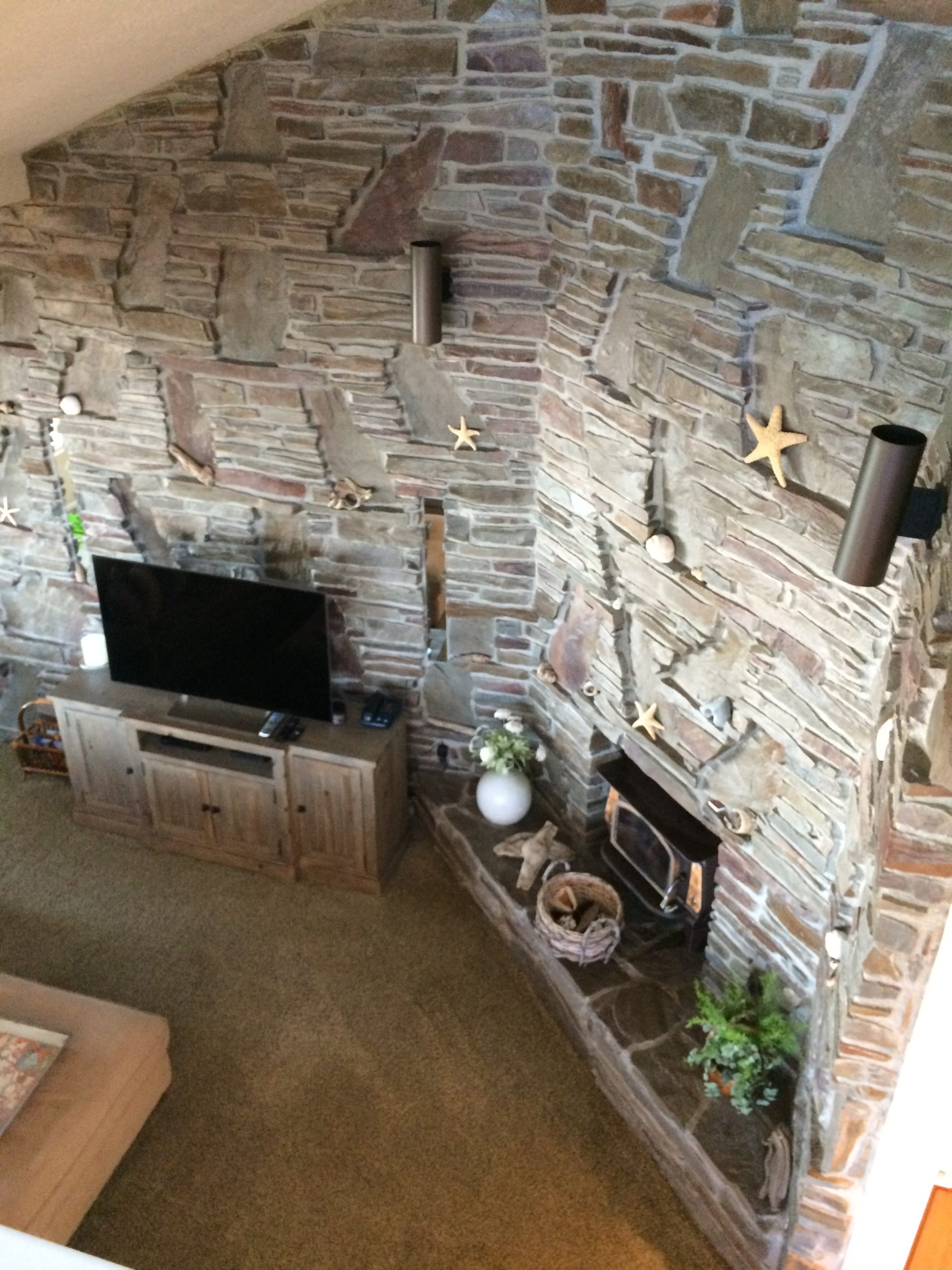 Photo looking down on stone wall and gathering space with electric fireplace at Pacific Edge
