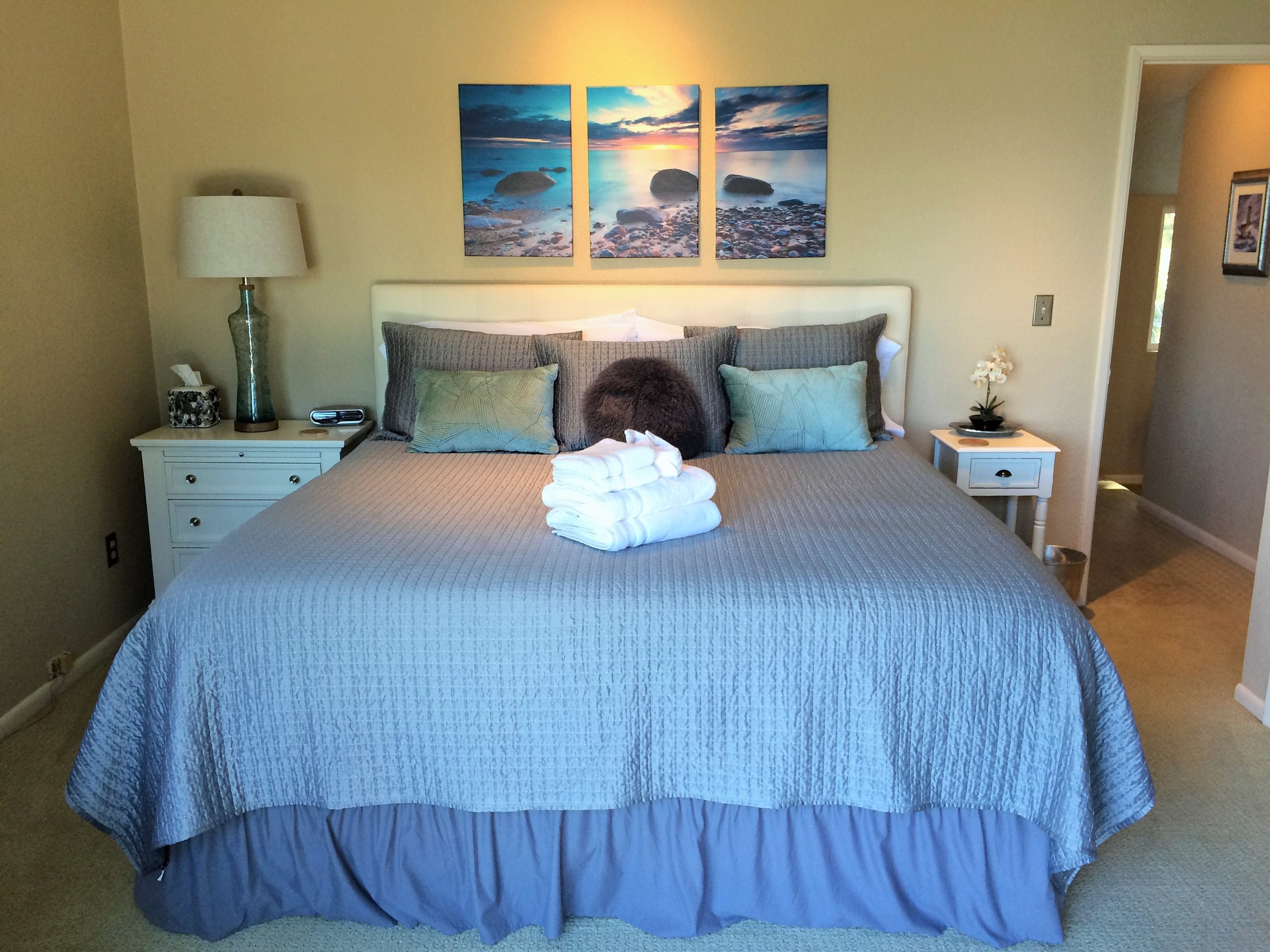 A bedroom at Pacific Edge with pleasant furnishings and ocean artwork