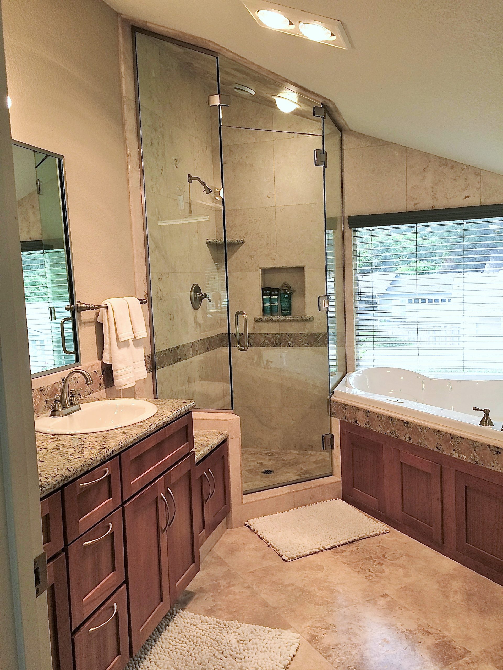 Photo of master bathroom with tile flooring and counters, modern glass shower and soaking bath