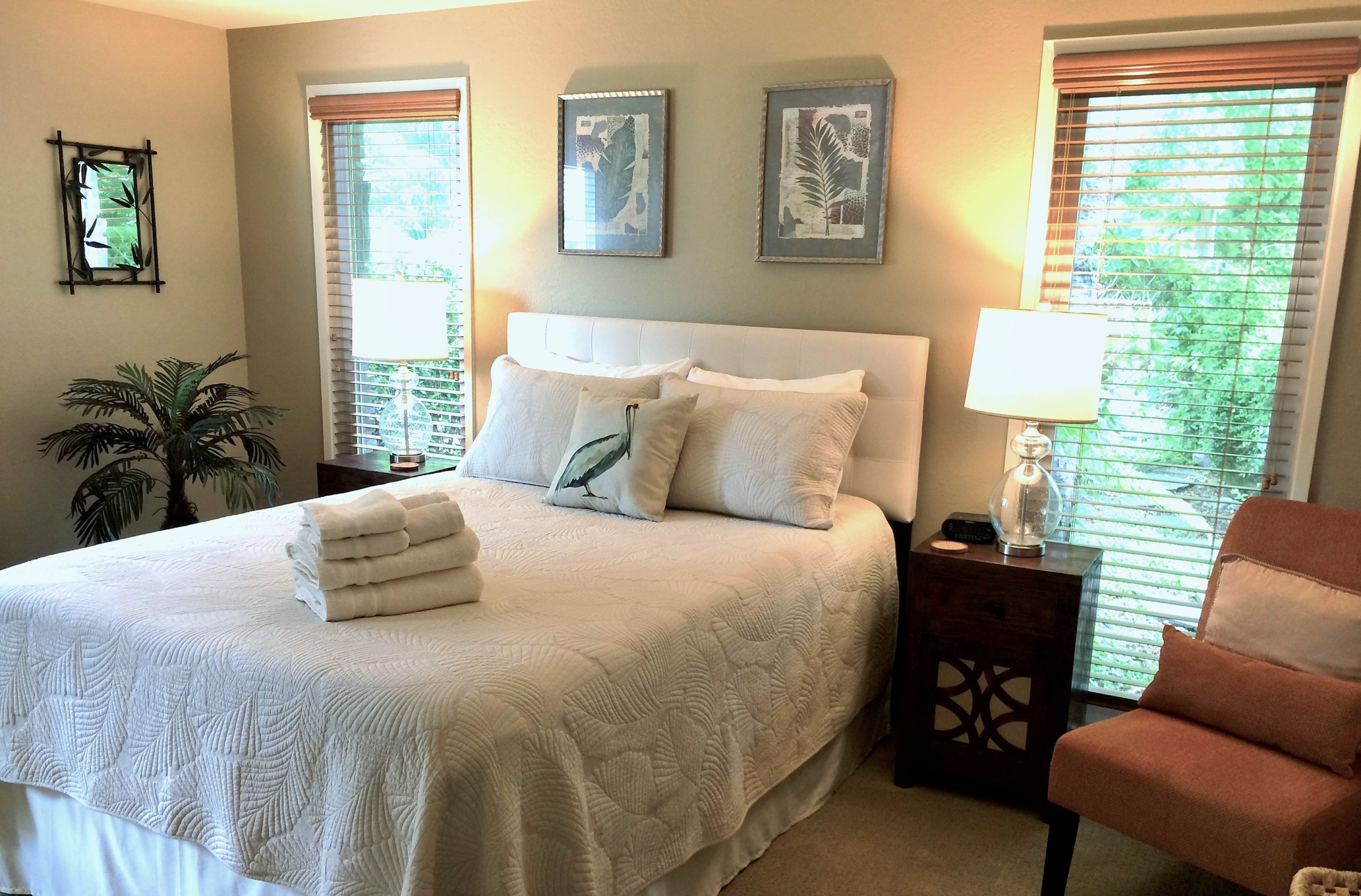 Photo of a bedroom at Pacific Edge - two tall windows overlooking greenery and landscaping