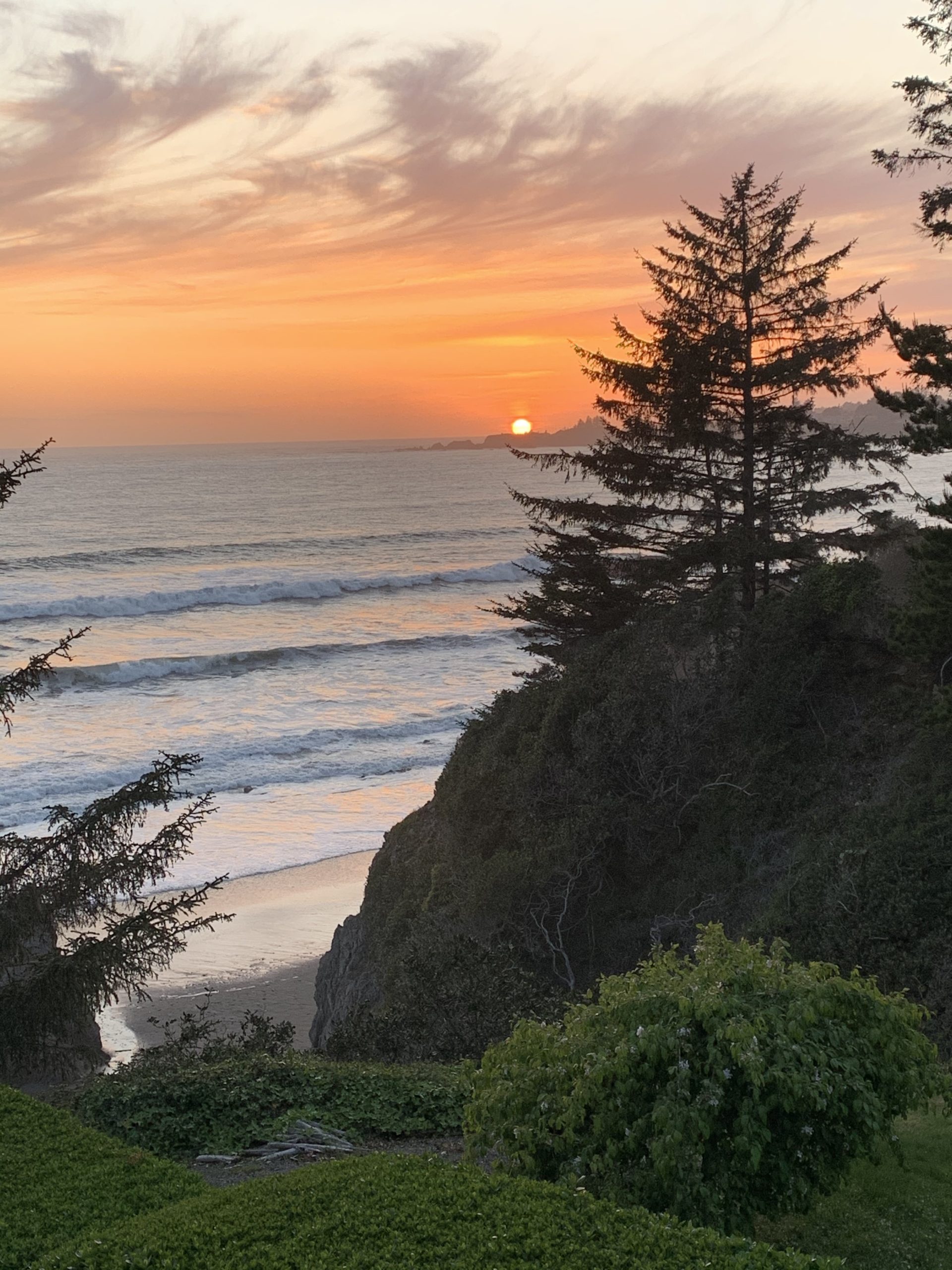 Photo of colorful sunset with oranges and yellow over the ocean from the cliffside