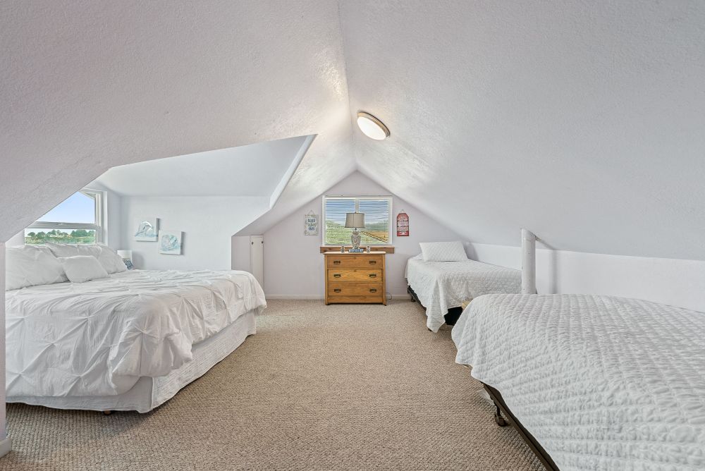 Photo of upstairs bedroom featuring queen bed and two twins in a unique attic room