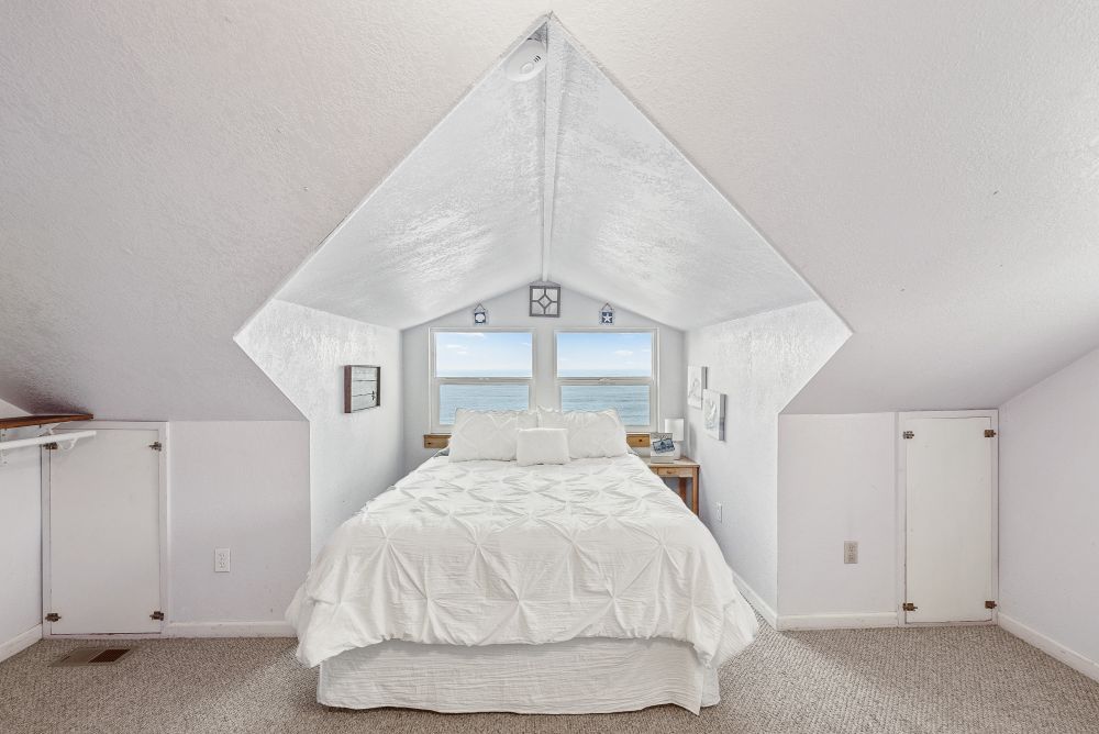 Photo of upstairs bedroom - with bed tucked into the unique architectural alcove with windows overlooking the ocean.